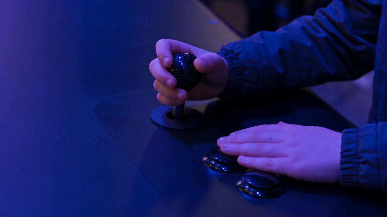 The boy's hands on the stage's play panel, a stick and two buttons